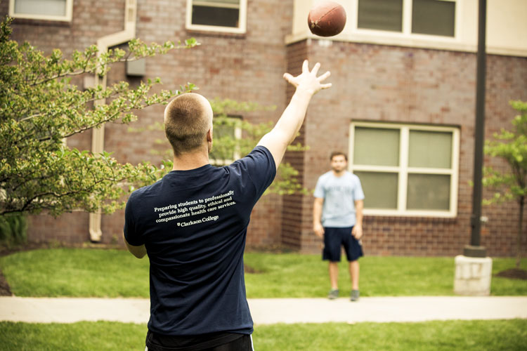 Students playing catch in the courtyard in front of the Residence Hall.